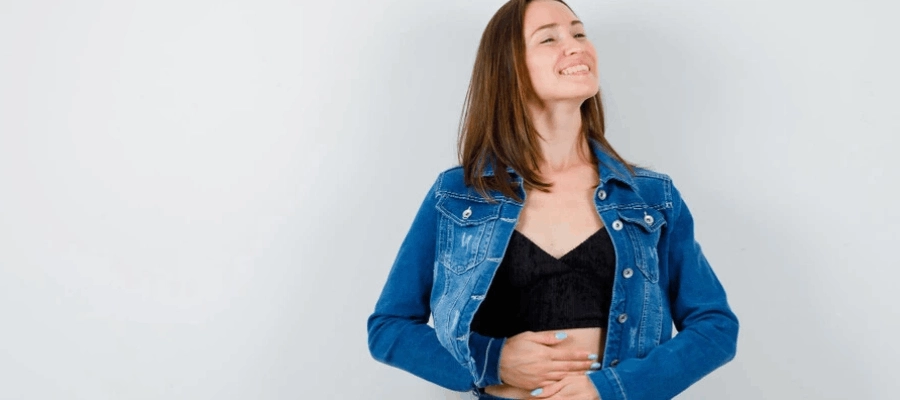 mulher feliz com as maos na barriga no tempo de digest